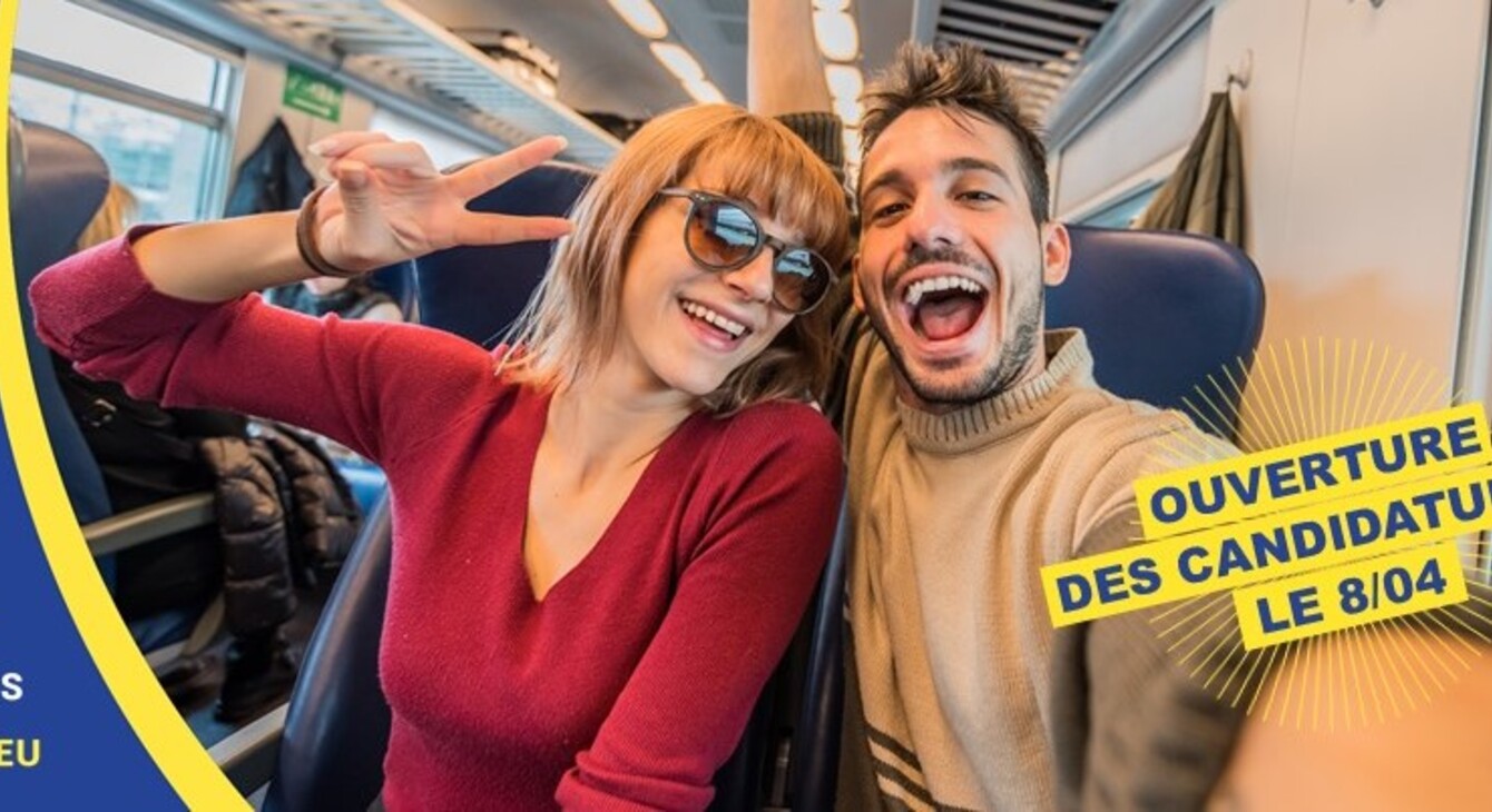 Une jeune femme et un jeune homme sont assis dans un tain. Ils sont très heureux de partir en voyage comme le démontre leurs visages très expressifs. Sur la gauche il est mentionné Élargis tes horizons #DiscoerEU tandis que sur la droite il est noté ouverture des candidatures le 8 avril. 