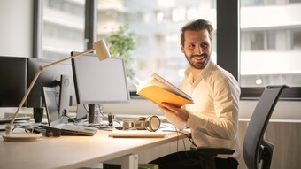 homme assis à son bureau avec un ordinateur et des dossiers