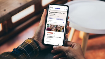 Image d'une personne tenant un téléphone qui affiche la page des missions du site jeveuxaider.fr