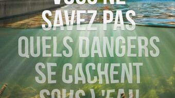 La photo présente un cours d'eau, on peut y voir la surface mais également sous l'eau, l'appareil prenant la photo étant à trois-quart immergé. À la surface un pont est présent en haut de la photo. L'eau semble calme et sécurisé, mais on peut voir en profondeur des débris métalliques dangereux pour les baigneurs. Au travers de l'eau on peut lire en écriture blanche "Vous ne savez pas quels dangers se cachent sous l'eau." Le texte prend une très grande partie du visuel. L'environnement autour du cours d'eau 