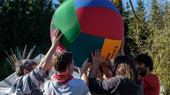 Des personnes tiennent une balle géante à plusieurs, jouant ainsi au kin-ball, dans un cadre ludique